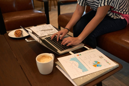 Hard-working manager wrapped up in work while sitting at cozy office lobby, cup of fragrant coffee...