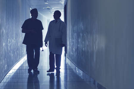 Two doctors walking along the corridor and communicatingの写真素材