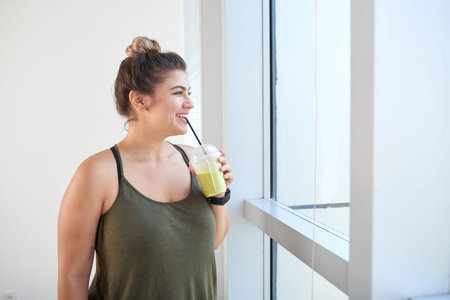 Woman with a smoothie standing at windowの写真素材