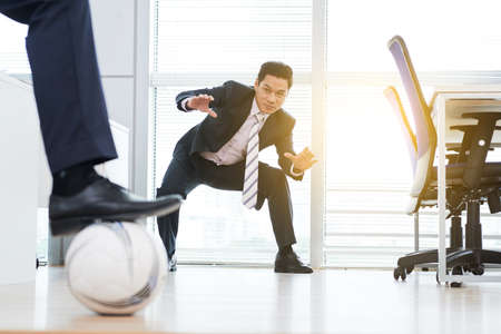 Businessmen playing football in officeの写真素材