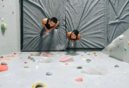 From above shot of man and woman preparing for wall ascend standing on mat and looking up in preparationの写真素材