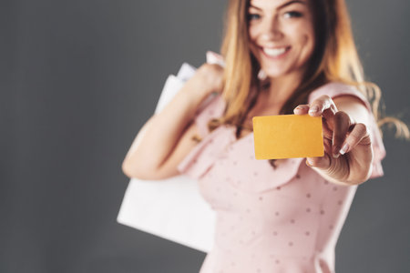 Happy woman with shopping bags showing discount card