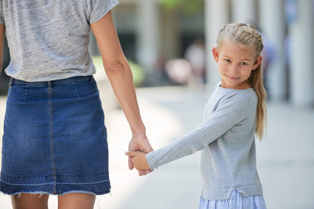 Girl and mother holding hand together