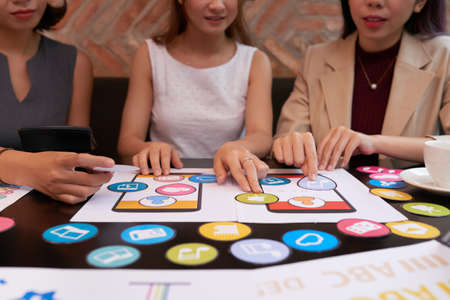 Samples of icons and smartphone screens on table on managers at brainstorming sessionの写真素材