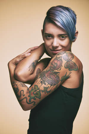Attractive stylish young woman with blue hair and tattoo on her armsの写真素材