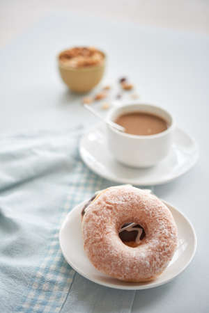 Served glazed doughnuts on small plate with cup of coffee on background composed on towel on tableの写真素材
