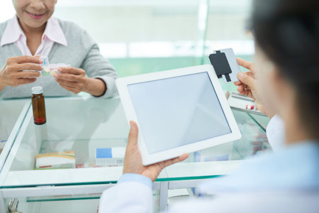 Pharmacist using credit card reader device attached to digital tablet