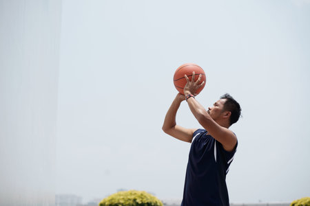 Filipno basketball player jumping and throwing ballの写真素材