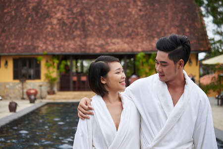 Hugging Vietnamese couple wearing bath robe after swimming in poolの写真素材