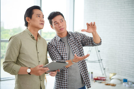 Mature Asian business collegues planning repairs of their officeの写真素材