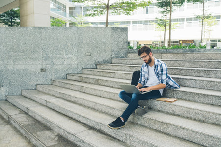University student resting on campus and working on laptop