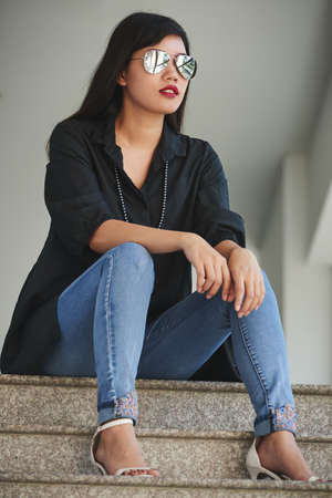 Attractive young stylish woman sitting on stairsの写真素材