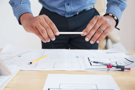 Crop unrecognizable Indian man taking shot of plans and papers with smartphone in officeの写真素材
