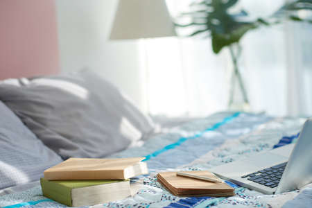 Notepad with pen, books and laptop on bed, selective focusの写真素材
