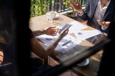 Cropped image of business people discussing documents with financial data at meeting in cafeの写真素材