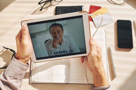 Businessman with tablet computer videocalling to Vietnamese coworker