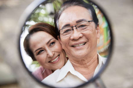 Happy smiling senior couple in reflection of scooter mirrorの写真素材