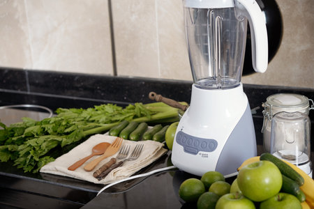 Various fruits and vegetables for yummy smoothie lying near blender on kitchen counter