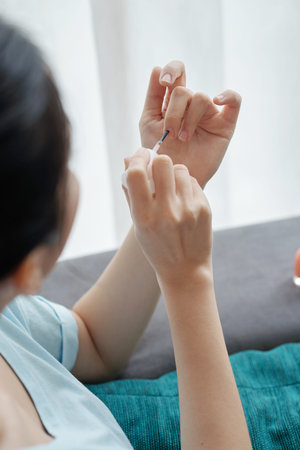 From above shot of unrecognizable woman using brush to apply nail polish on fingernailsの写真素材
