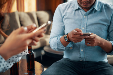 Faceless shot of man and woman using smartphone while relaxing together in separation