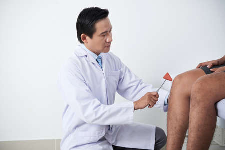 Surgeon examining knee reflexの写真素材