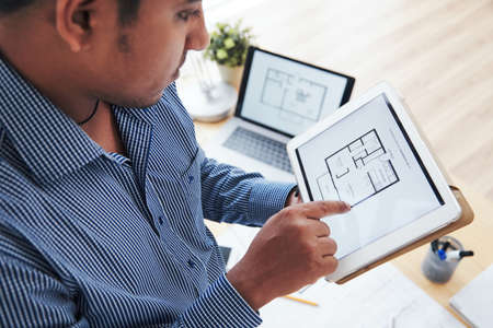 Engineer examining apartment plan on tablet computerの写真素材