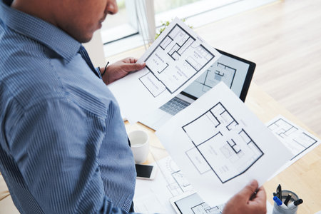Interior designer looking at documents with apartment blueprints in his hands