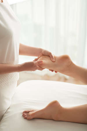 Woman massaging feet of female client in spa salonの写真素材