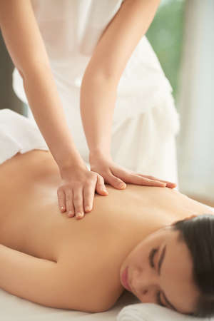 Young Asian woman enjoying back massage in spa salonの写真素材