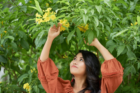 Smiling attractive young woman standing under blooming treeの写真素材