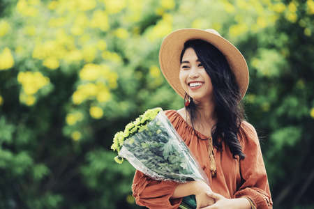 Attractive Vietnamese woman with beautiful toothy smile and bouquet of flowersの写真素材