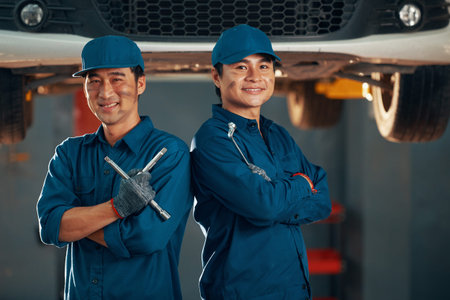 Smiling Asian car service workers standing with folded armsの写真素材