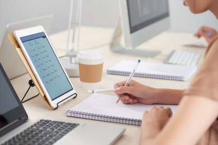 Student copying data from tablet computer to textbook during English class
