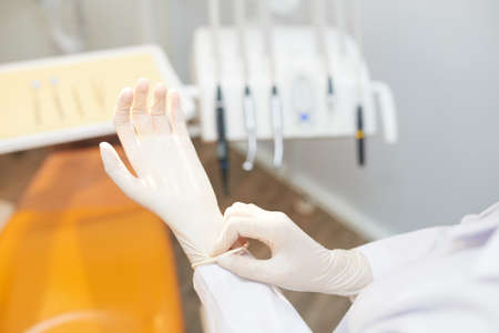 Crop shot of doctor in dental office putting on white latex gloves before procedureの写真素材