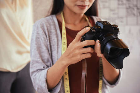 Unrecognizable fashion designer holding professional camera and looking at pictures of outfit on itの写真素材