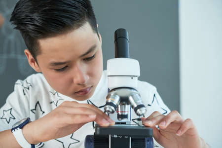 Schoolboy working with microscopeの写真素材
