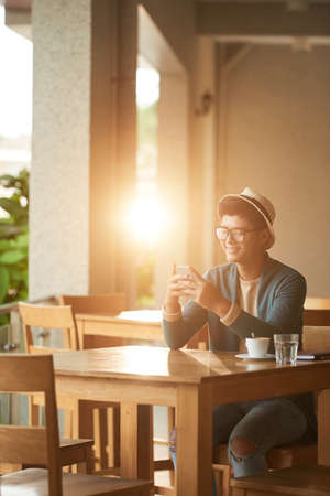 Cheerful texting man in cafeの写真素材