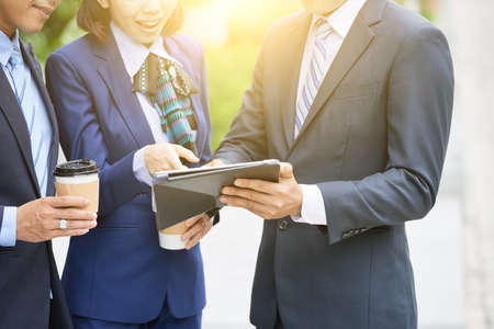 Crop shot of modern elegant men and woman standing with coffee on street and sharing tabletの写真素材