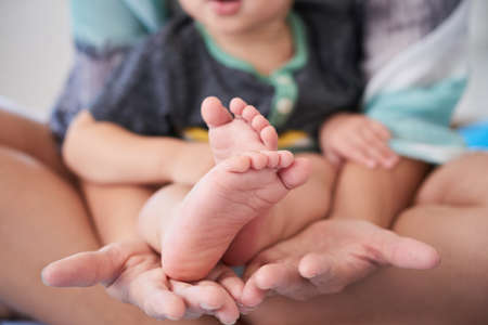 Close-up of mother holding little barefooted son on her handsの写真素材