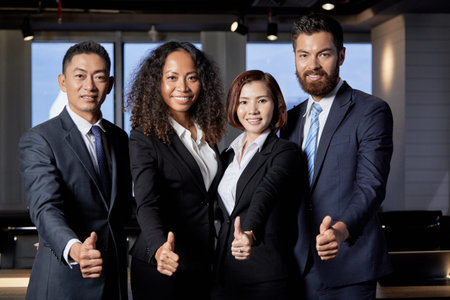 Group of successful young multiethnic men and women standing together and showing thumbs up