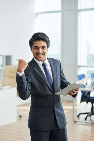Businessman standing with notepad at office and he is happy because he did all his workの写真素材
