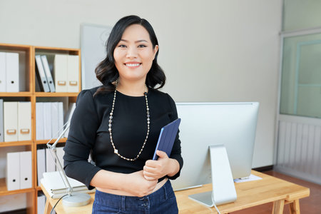 Pretty successful business lady with tablet computer standing in office