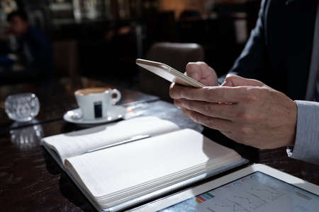 Smartphone in hands of entrepreneur who is spending lunchtime in restaurantの写真素材