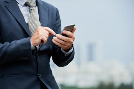 Cropped image of bsuinessman answering text messages