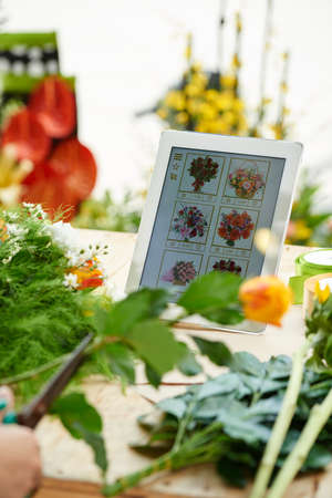 Digital tablet with flower shop application and orders from clients on table of floristの写真素材
