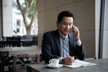 Mature entrepreneur checking planner when making appointment on the phone