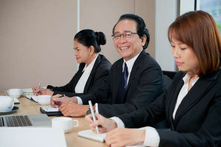 Portrait of cheerful senior businessman attending meeting with coworkersの写真素材