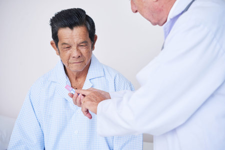 Unrecognizable medical practitioner explaining elderly patient how to use prescribed medicine while...