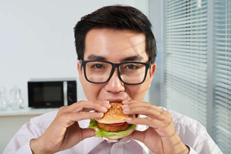 Businessman eating hamburgerの写真素材