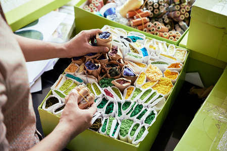 Close-up of man unpacking cardboard boxes with colorful threads   in atelierの写真素材